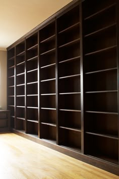 an empty room with many bookshelves in the center and wood flooring on the other side