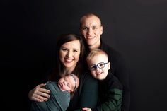 a man, woman and child are posing for a photo while holding their newborn baby