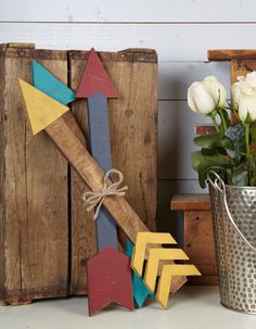 a metal bucket with flowers in it sitting next to wooden blocks and an arrow sign