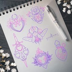 a notebook with some drawings on it next to flowers and a ballpoint pen,