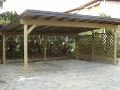 a covered patio area in the middle of a yard with trees and bushes behind it