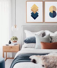 a bedroom with two paintings above the bed