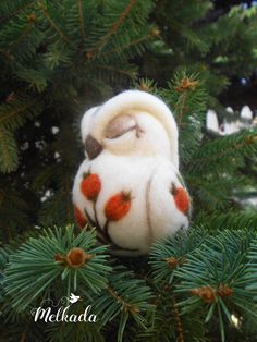 a small stuffed animal sitting on top of a pine tree