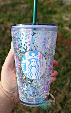 a person holding up a starbucks cup with glitter and a green straw in her hand