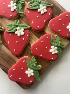 strawberry cookies decorated with royal icing on a cutting board