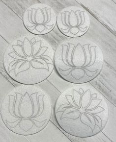 four coasters with flowers on them sitting on a wooden table next to each other