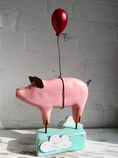 a pig with a red balloon attached to it's back sitting on top of a box