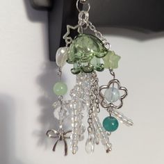 a green and white necklace hanging from a hook on a door handle with charms attached to it