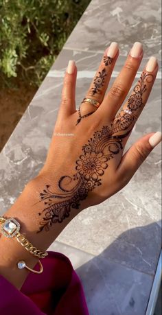 a woman's hand with henna tattoos on it