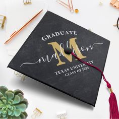 a black graduation cap with the letter m on it and tassels around it