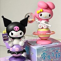 two figurines sitting on top of each other in front of a box that says hello kitty