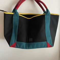 Tote Bag In Canvas Material. Never Worn Before. Is In Excellent Condition. A Nice Wide Tote Bag That Can Hold Alot Of Things. The Multiple Colors On This Bag Makes It A Dress Up/Down Bag. Inside This Bag Has A Zipper For Closing. Has A Zippered Pocket On The Inside With An Additional Small Pocket For Holding Stuff. Also Has A Back Pocket For Holding Items. It Is Not Super Long But Is Supwer Wide. Measurements Can Be Found Below: Measurements: Length - 11 Inches Width - 20 1/4 Inches Retro Black Canvas Bag For Daily Use, Casual Black Color Block Bag, Retro Black Canvas Bag For Travel, Black Retro Canvas Bag For Travel, Retro Black Canvas Travel Bag, Black Color Block Bags For Daily Use, Black Color Block Bag For Daily Use, Black Color Block Shoulder Bag For Everyday Use, Everyday Use Black Color Block Shoulder Bag