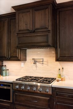 a stove top oven sitting inside of a kitchen next to wooden cabinets and white counter tops