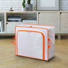 an orange and white storage bag sitting on the floor in front of a brick wall