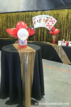 a table topped with balloons and cards on top of a black table cloth covered table