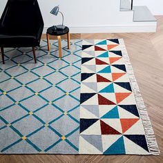 an area rug with various colors and shapes on the floor next to a black chair