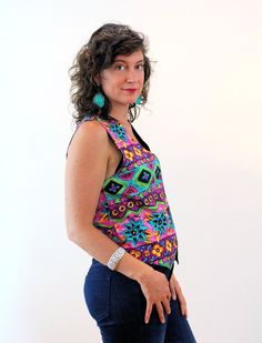 "This is a cheerful 90s vintage buttery soft rayon vest in bright, almost neon, lime green, purple, pink, blue and yellow! The print combines stylized flowers with zig zag stripes and geometric shapes. It has ties at the back to adjust the waist and it's fully lined with black satin inside. It closes with three large clear and black striped plastic novelty buttons. The vest is in very good clean vintage condition, no flaws noted. The label says \"Accordeon, Body 100% Rayon, Lining 100% Acetate, Retro Multicolor Summer Vest, Multicolor Retro Summer Vest, 90s Style Spring Vest, Multicolor Sleeveless Top With Buttons, Vibrant Fitted Sleeveless Top, Retro Fitted Summer Vest, Colorful Fitted Vibrant Top, Retro Fitted Vest For Summer, Fitted Retro Vest For Festivals