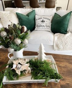 a tray with flowers and greenery on top of a table in front of a couch