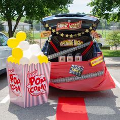 two popcorn boxes sitting in the middle of a parking lot next to a movie car