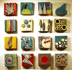 nine colorful ceramic tiles are arranged on a wall in an art gallery, each with different shapes and sizes