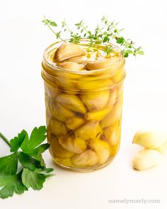 a jar filled with pickled potatoes next to some parsley on the counter top