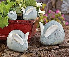 two ceramic rabbits sitting next to a potted plant