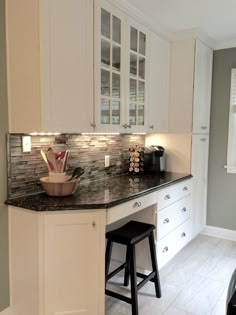 a kitchen with white cabinets and black counter tops