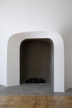 an empty fireplace in a white walled room