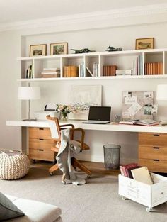 a home office with white walls and shelving above the desk is filled with books