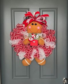 a door hanger with a teddy bear wearing a red and white wreath on it