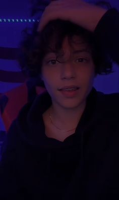 a young man with curly hair wearing a black hoodie