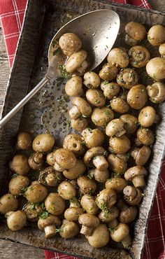 a tray filled with potatoes on top of a red and white checkered table cloth