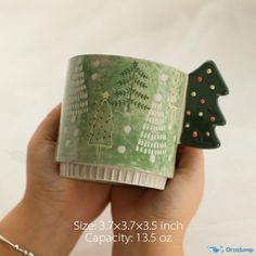 a hand holding a green cup with christmas trees on it