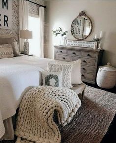 a bedroom with a bed, dresser and mirror on the wall next to a window