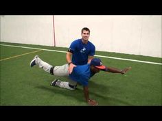 two men are playing frisbee in an indoor field with one man falling to the ground