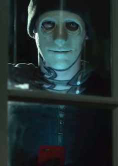 a creepy man looking through a window at the camera