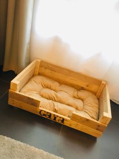 a dog bed made out of wood with the word cat on it in front of a window