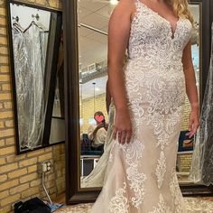 a woman standing in front of a mirror wearing a wedding dress