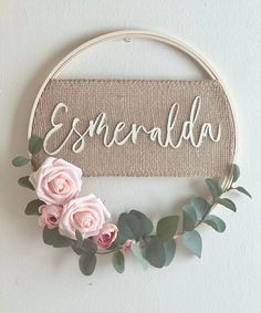 a sign that says esmerallda hanging on the wall next to some pink flowers