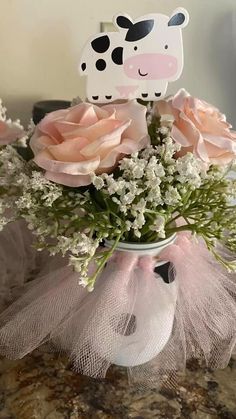 a vase filled with pink roses and baby's breath in front of a cow cutout