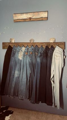 several pairs of jeans hanging on a wooden rail