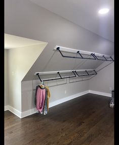 an empty room with some clothes hanging on the wall and a coat rack in the corner