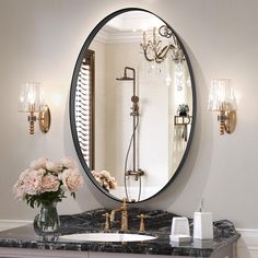 a bathroom with marble counter top and round mirror above the sink, gold faucet