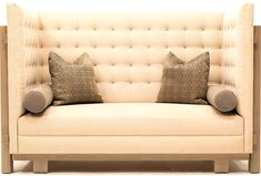 a beige couch with two pillows on it's back and one pillow sitting on the arm