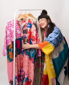 a woman standing next to a rack with clothes on it