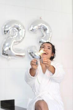 a woman in a bathrobe is holding sparklers