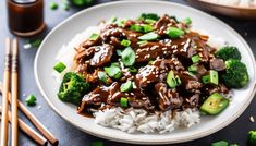 a white plate topped with rice and beef covered in sauce next to chopsticks