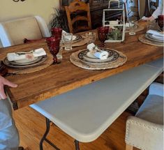 a man standing in front of a wooden table with plates and silverware on it