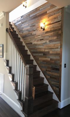 a wooden stair case next to a light on the wall