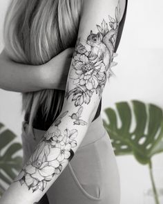 a woman's arm with flowers and leaves tattooed on the arm, in black and white